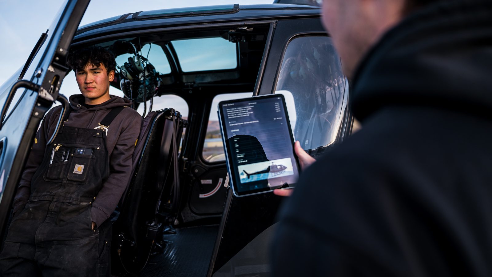 Helicopter crew reviewing the ROTYR app on a tablet beside the aircraft